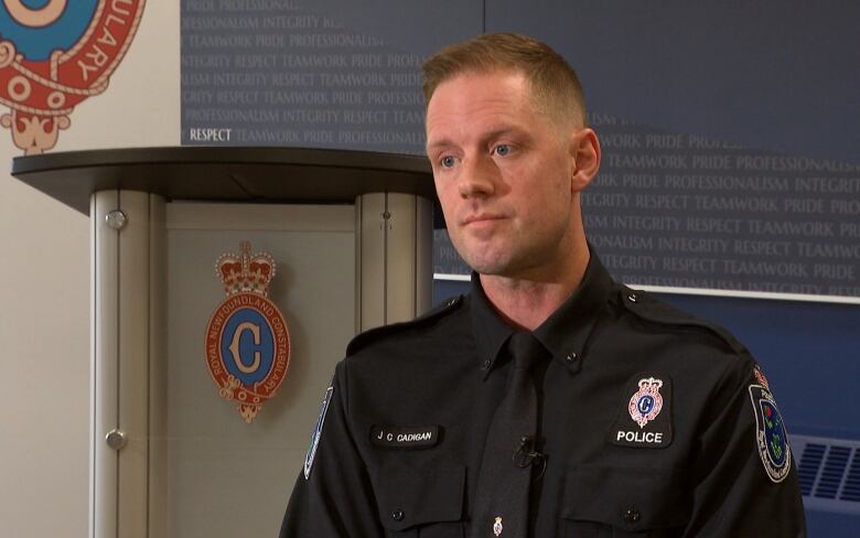 A man wearing a police uniform sits in front of a podium.