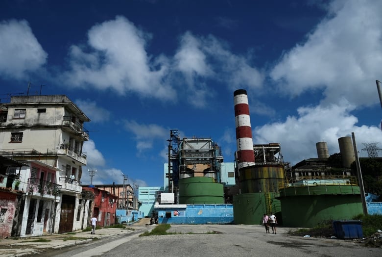 People walk past a thermo-electric power plant in Havana, Cuba.