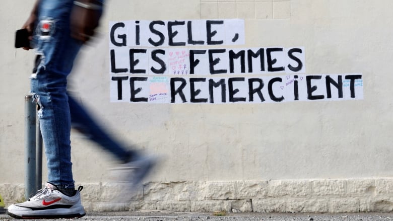 A shot of legs walking past French graffiti that says 'Gisele, Women thank you' 