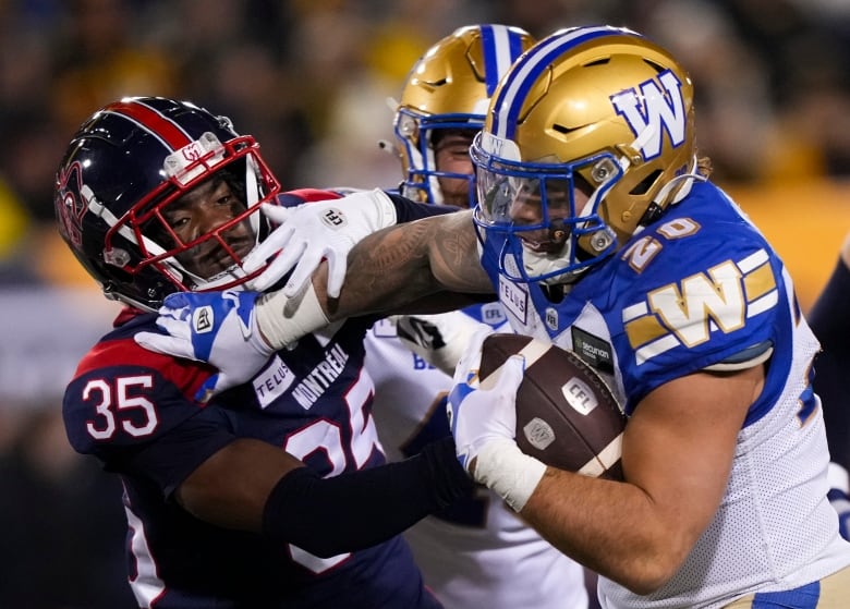 A football player runs with a ball, trying to break a tackle.