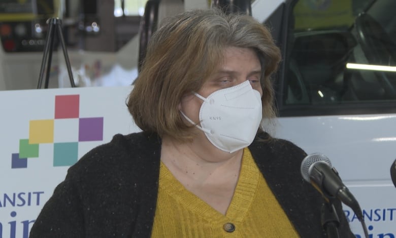 Woman with grey hair wearing a mask. 