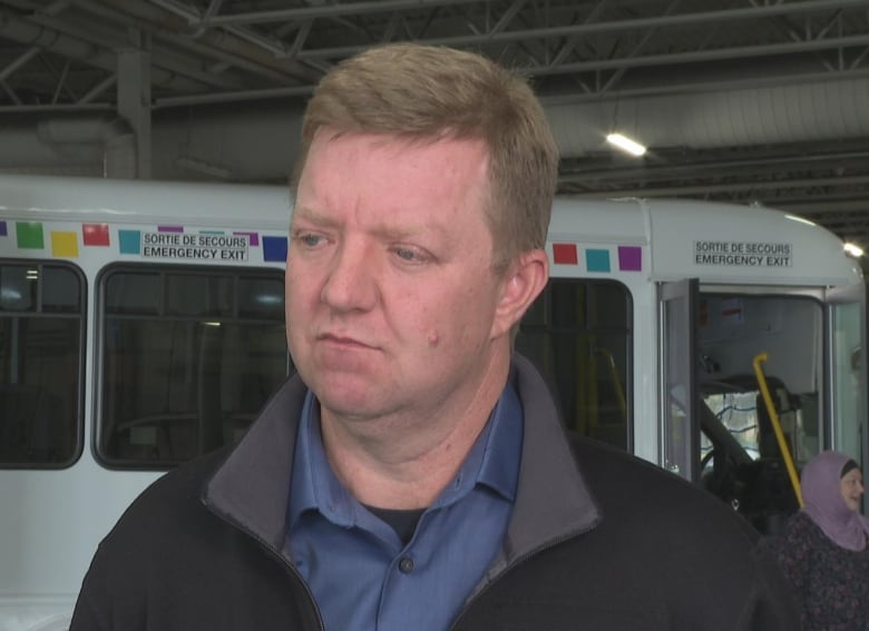 Man with short hair looking at camera with neutral expression.