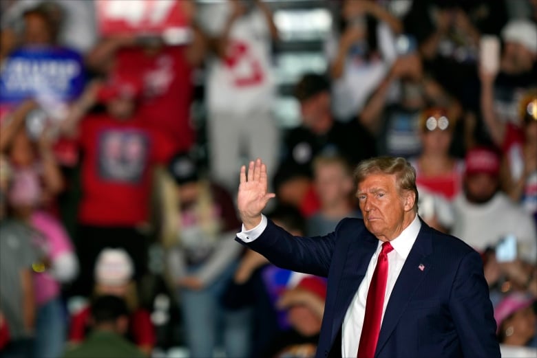 A man in a  suit waves  at supporters