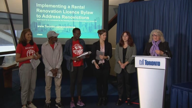 Photo of a city councillor standing next to activists at a podium