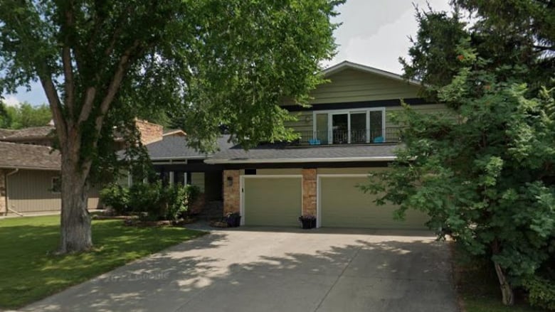 a two-storey home with two large green trees in front