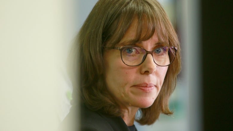 A woman with glasses and brown hair.