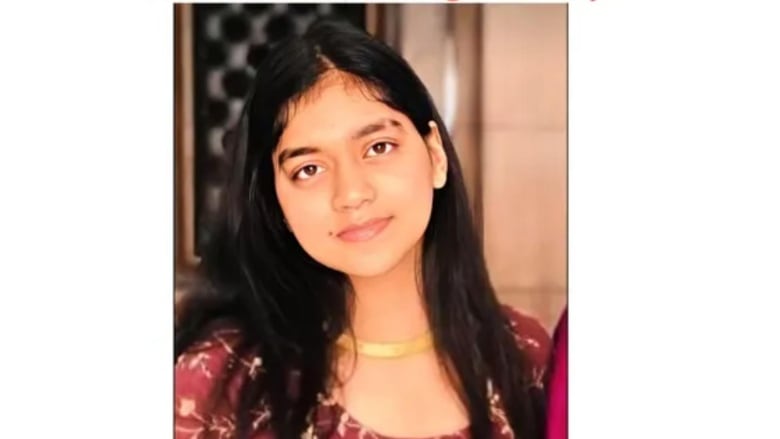 A young woman with long dark hair looks at the camera. 