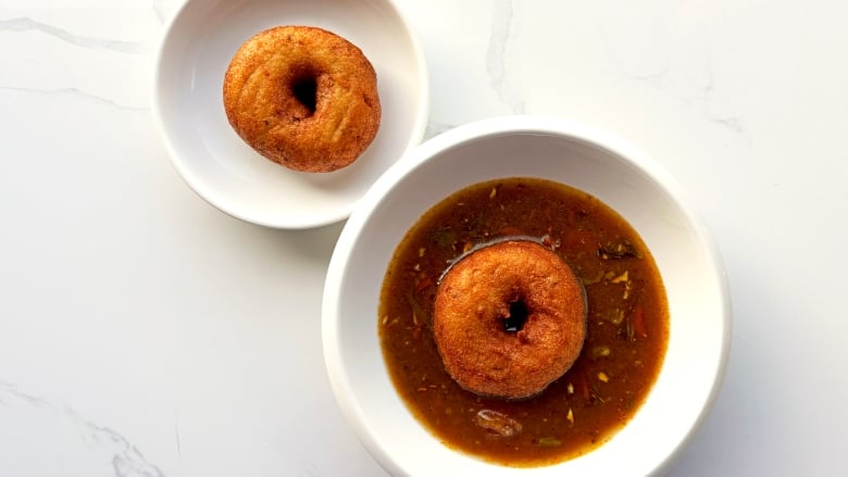 A bowl of rasam soup topped with vadai