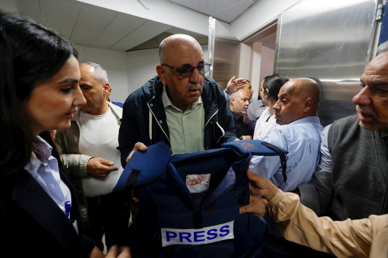 A man holds up a blood flak jacket.