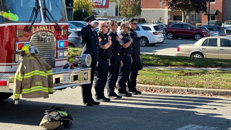 Five men standing in beside a firetruck.