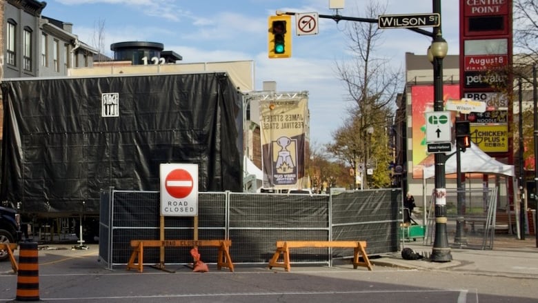 A city street marked closed with a sign and physical barriers. 