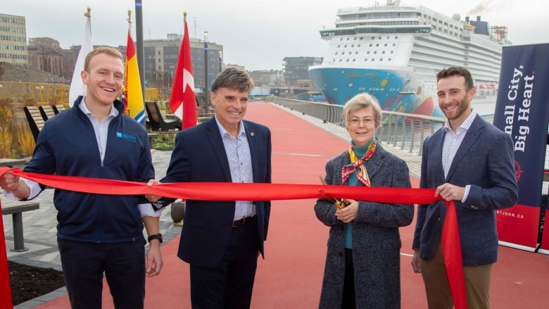 Four people. One woman, three men, ceremoniously cutting a ribbon.  