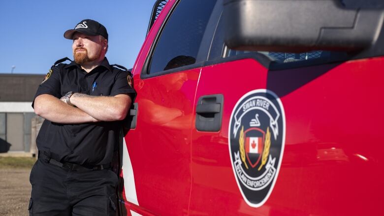 A bylaw officer leans against a truck.