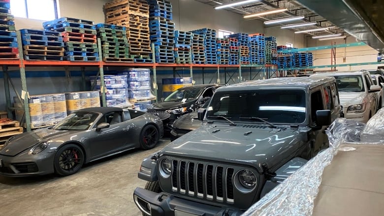 Several cars lined up in a warehouse-like building.