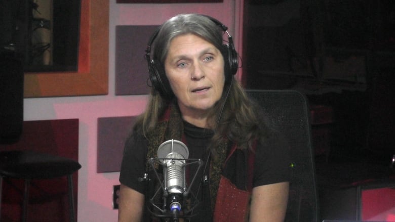 Woman with long grey hair talking into radio mic