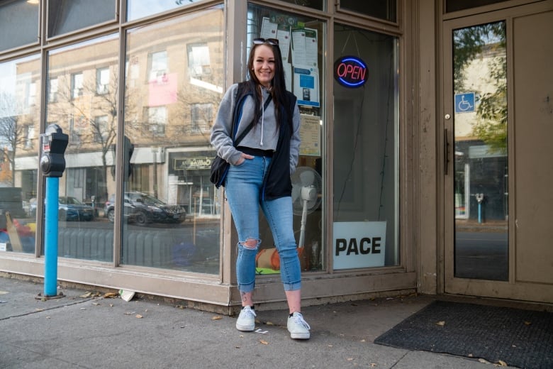 A person is seen standing outside a building. They are smiling.