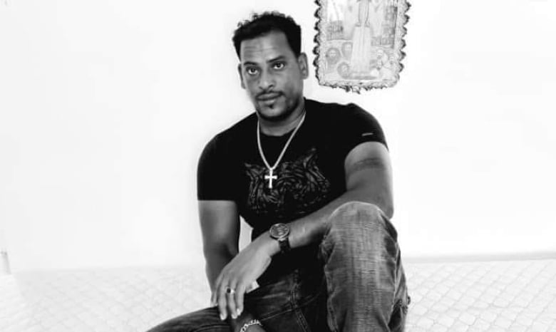 A black and white photo of a man sitting on the floor.