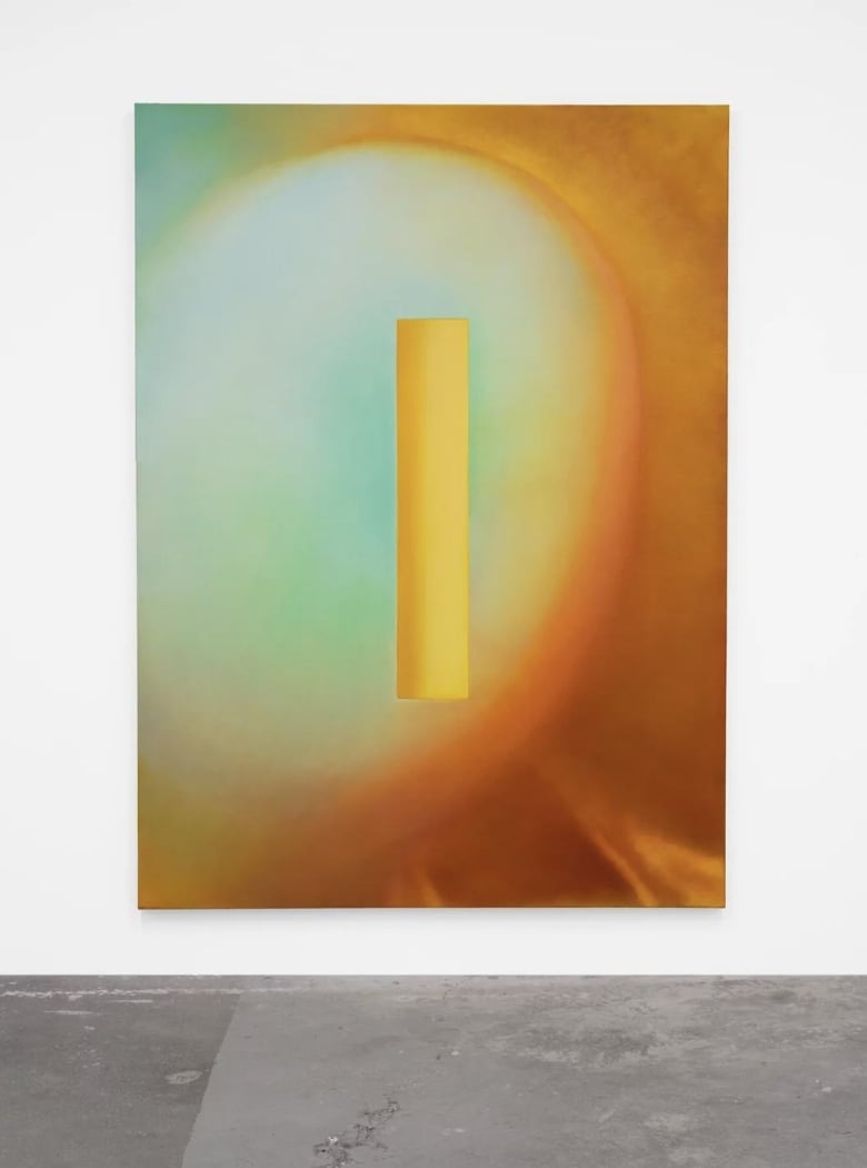 Abstract painting in glowing oranges, yellows and greens, hangs on a white wall.