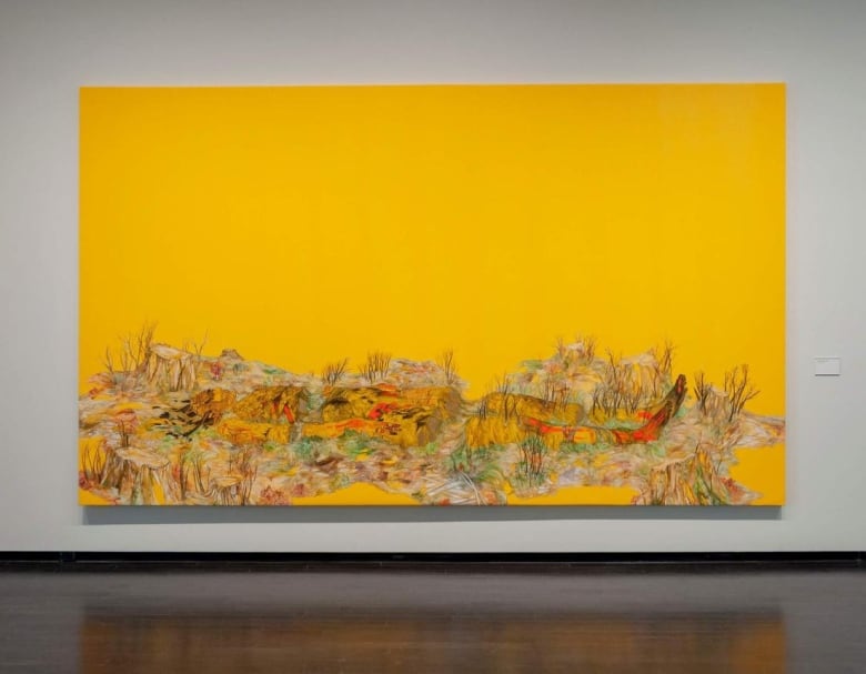 Large painting hanging on a white wall. The background is uniformly yellow. The base depicts a female form that appears to be as one with the grass and tree stumps on the ground.