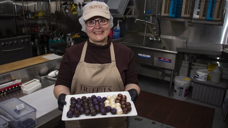 A woman holds a palte of truffles.