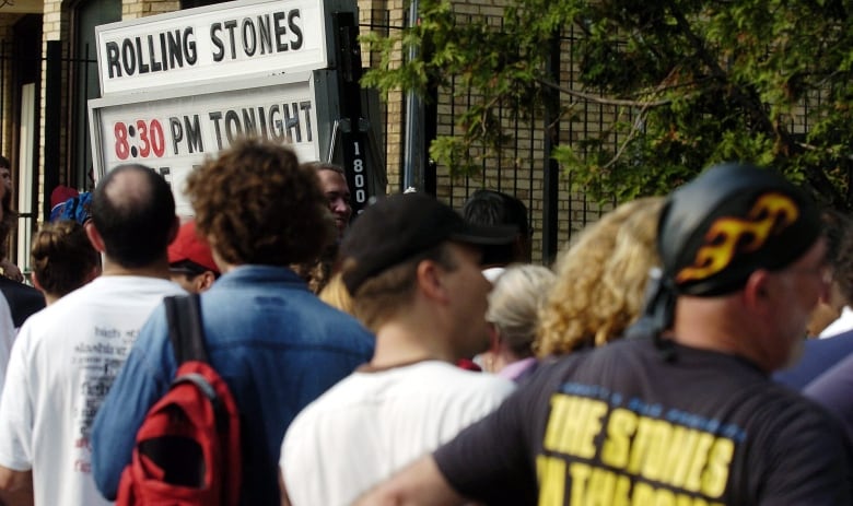 A lineup of people is visible, with a sign in the distance saying 