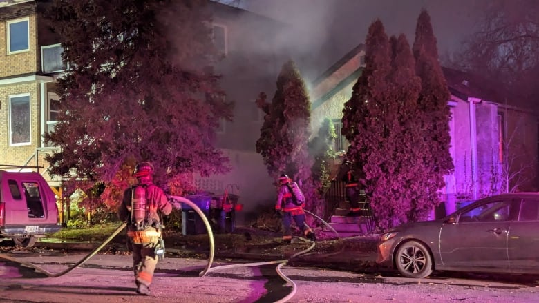 Fire crews outside a house with a hose as smoke billows.