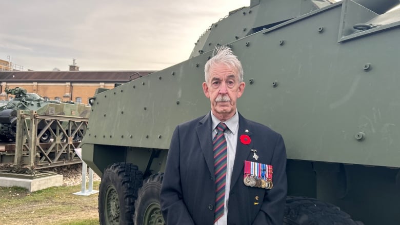 A man standing in front of an armored vehicle.