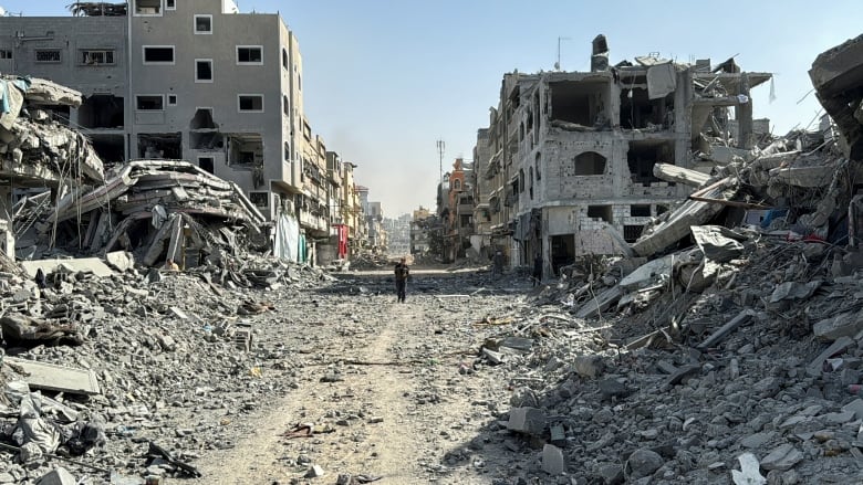 A person walks through rubble.