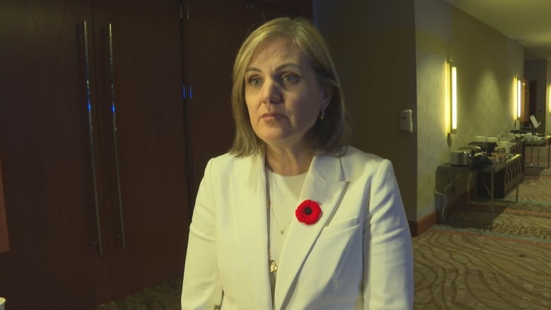 Melanie Fraser, wearing a poppy, stands in a hall.