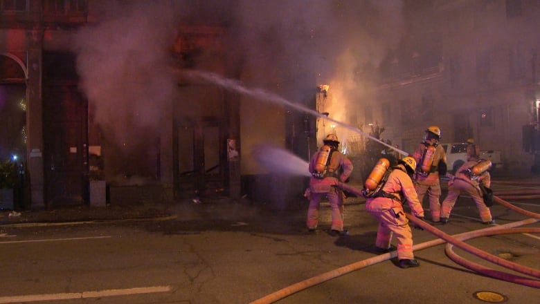 firefighters spray water at an old building at night