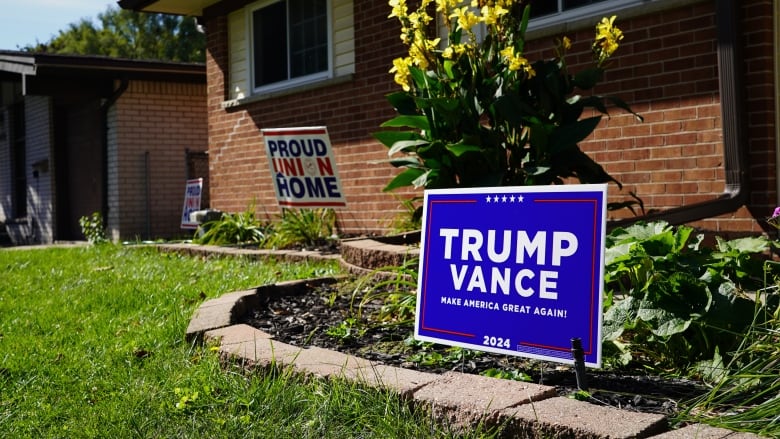 Two lawn signs are pictured on a front lawn in front of a brick rancher: one supporting unions and one supporting Republican candidate Donald Trump.