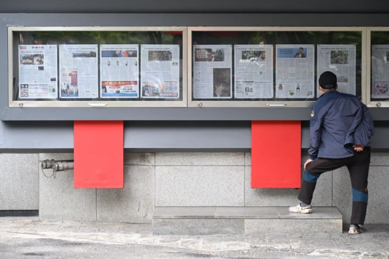 A man in Seoul reads a newspaper that features coverage of North Korea's decision to send thousands of troops to Russia for presumed involvement in Russia's fight with Ukraine.