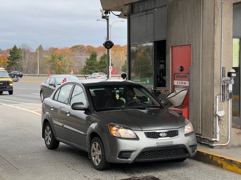 A grey car stopped at bridge toll. 