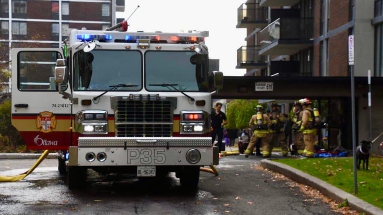 Firefighters outside a high-rise on an autumn day.