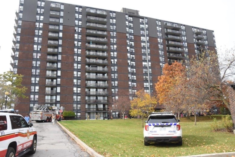 A high-rise brick building with fire trucks out front.