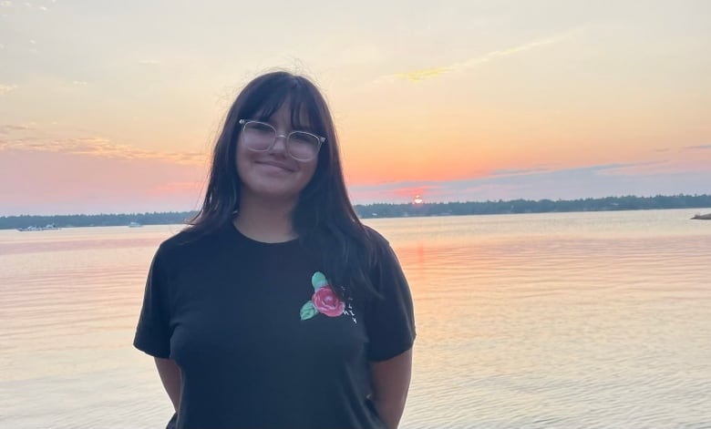 teenager stands in front of lake