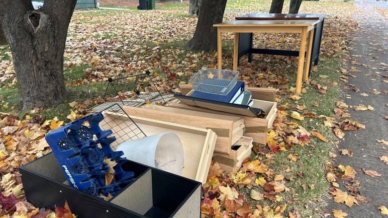 Shelves, drawers, tables and other waste at the curb under trees in fall.