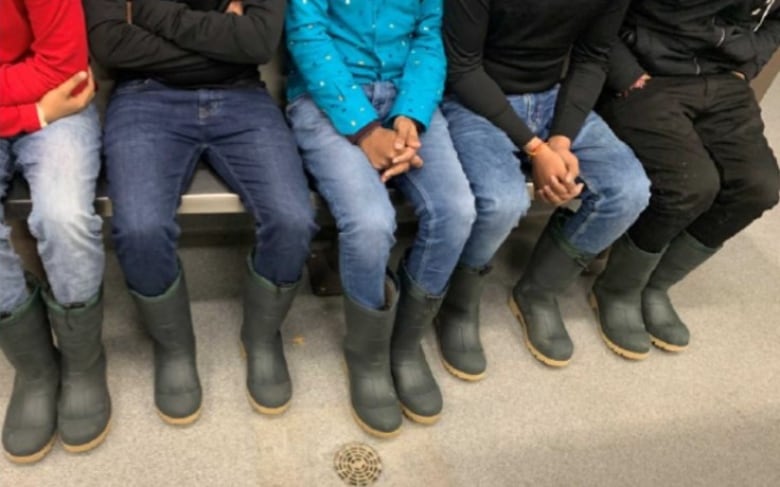 The knees and legs of fives people wearing rubber boots