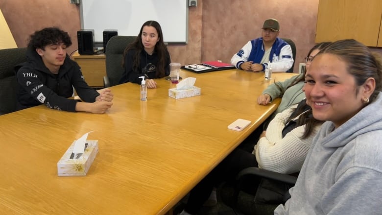 Youth sitting around a boardroom table 