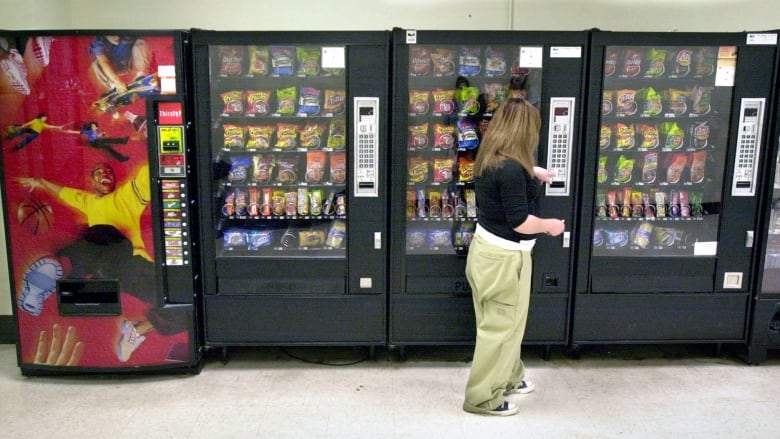 A customer at a junk food vending machine at a school.