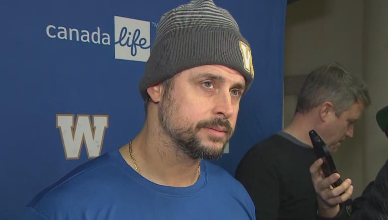 A man in a blue hat and shirt looks forward.