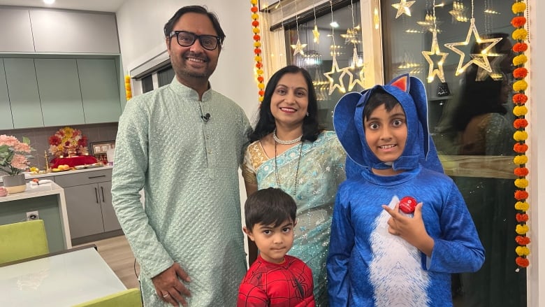 Two adults wearing traditional Indian attire with two children in a Spiderman and a Sonic the Hedgehog costume.