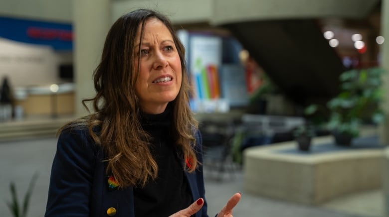 A woman is wearing a blazer and black turtleneck.