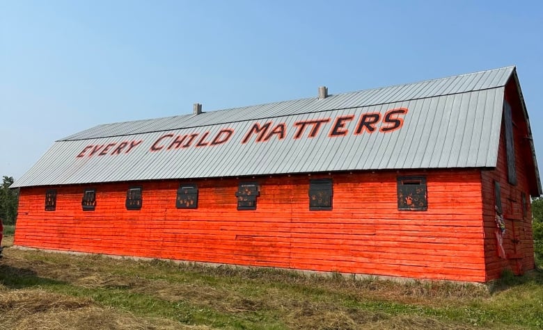 A barn painted orange with the words 'Every Child Matters' painted onto the rooftop