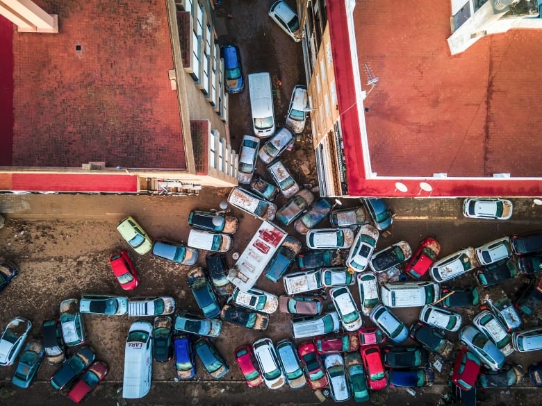 An aerial view shows upturned cars on a muddy street following a heavy storm.