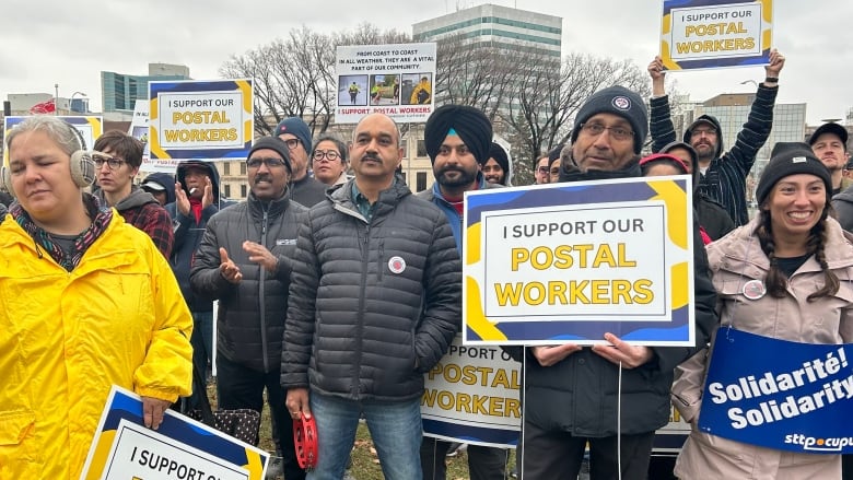 People holding signs saying 'I support postal workers'