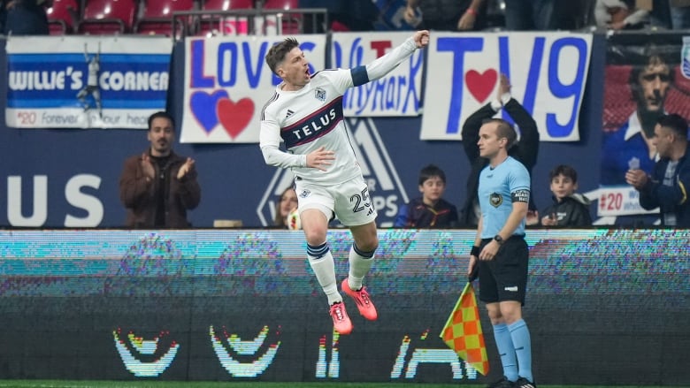 A player celebrates and jumps in the air during a soccer match. 