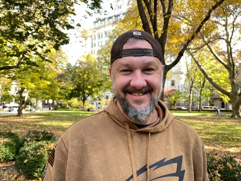 A man wearing a baseball cap is pictured in a park.