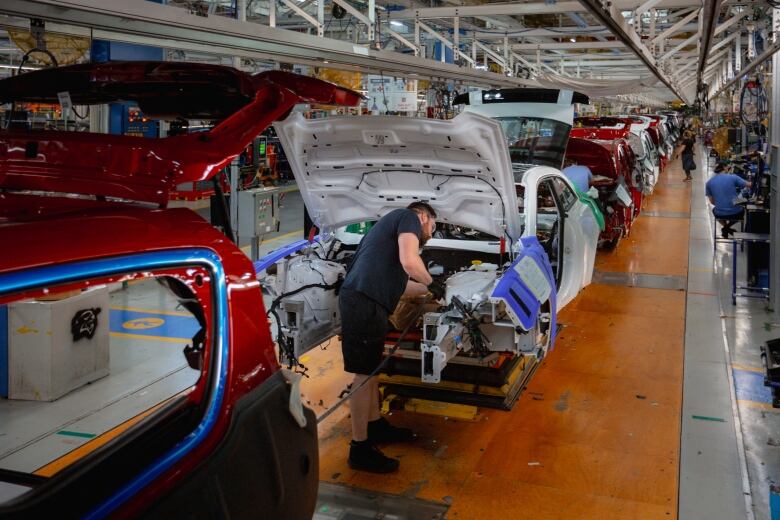 An employee at the Stellantis Windsor Assembly Plant works on the line assembling a vehicle inside of the region's largest employer. 