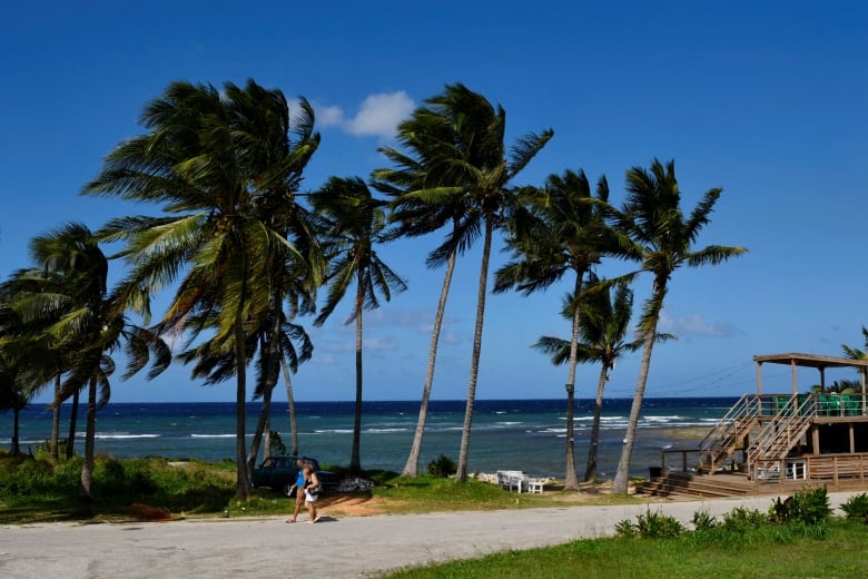 People walk near the beach as Tropical Storm Rafael approaches, in Playa Baracoa, Cuba, November 4, 2024.